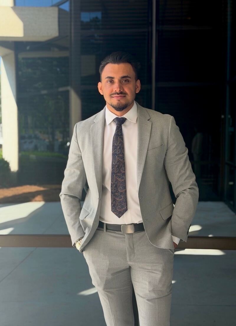 Ahmad of Mainline Strategies standing outside the Virginia Beach office in a tailored suit