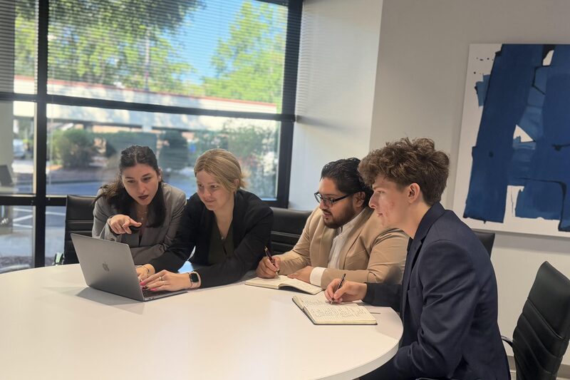 Four Mainline Strategies team members reviewing results together on a laptop in the office conference room